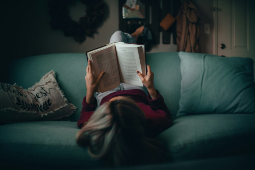 women in a red jumper reading on a sofa